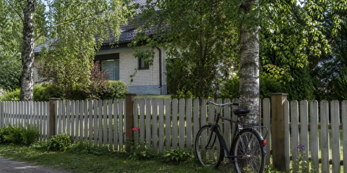 Puinen piha-aita koivujen ympäröimässä omakotitalopihassa.